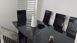 A dining table with six chairs, a tissue box, a small bag, and a glass of juice. - Immaculate 4-bed House in Chelmsford (Chelmsford)