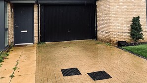 A modern building with a black facade, a large garage door, and a small tree in the yard. - Immaculate 4-bed House in Chelmsford (Chelmsford)