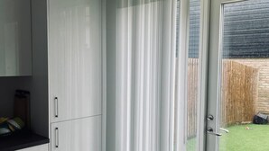 A modern kitchen with white cabinets and a sliding glass door leading to a backyard. - Immaculate 4-bed House in Chelmsford (Chelmsford)