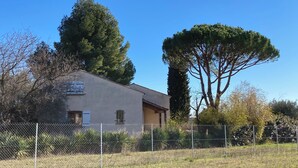Un bâtiment d’un seul étage, à la façade beige, doté d’un petit porche et d’une clôture en treillis métallique en premier plan.