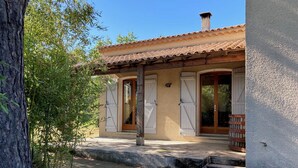 Un bâtiment avec un toit en tuiles, des volets en bois et un mur en pierre.