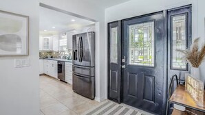 A modern kitchen with stainless steel appliances, a black door, and a sign reading "Beach House". - Dog-friendly home w/ private pool & outdoor living (Cape Coral)