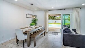 A modern living room with a dining area, a sofa, a bench, and a pool view. - Dog-friendly home w/ private pool & outdoor living (Cape Coral)