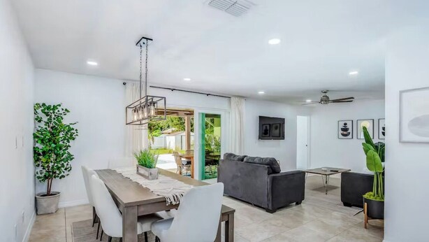 A modern living room with a sofa, a dining table with chairs, and a ceiling fan. - Dog-friendly home w/ private pool & outdoor living (Cape Coral)