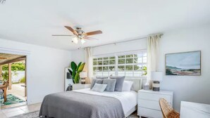 A bedroom with a bed, bedside tables, a ceiling fan, a window, and a view of the outdoors. - Dog-friendly home w/ private pool & outdoor living (Cape Coral)