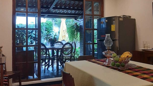 A dining area with a table set for two, a refrigerator, and a view of the outdoors. - Tekla Dorms (Santa Tecla)