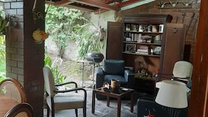 A cozy living area with a brick wall, a bookshelf, a sofa, and a dining table with chairs. - Tekla Dorms (Santa Tecla)