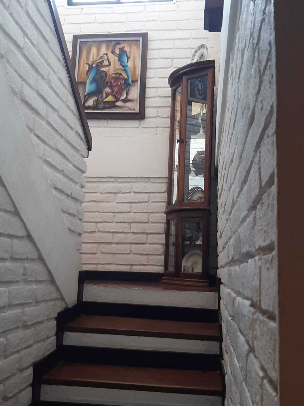A staircase with white brick walls and a wooden cabinet with glass doors.