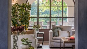 Un accogliente soggiorno con un'ampia finestra ad arco, un soffitto in legno e una zona salotto confortevole con divano e poltrone.