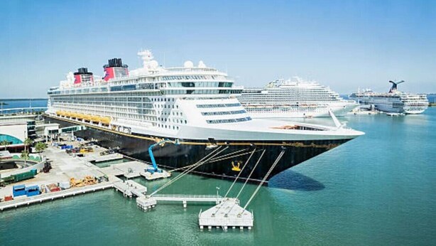 Ein großes Kreuzfahrtschiff liegt im Hafen, mit mehreren Decks und einer markanten Bugpartie.