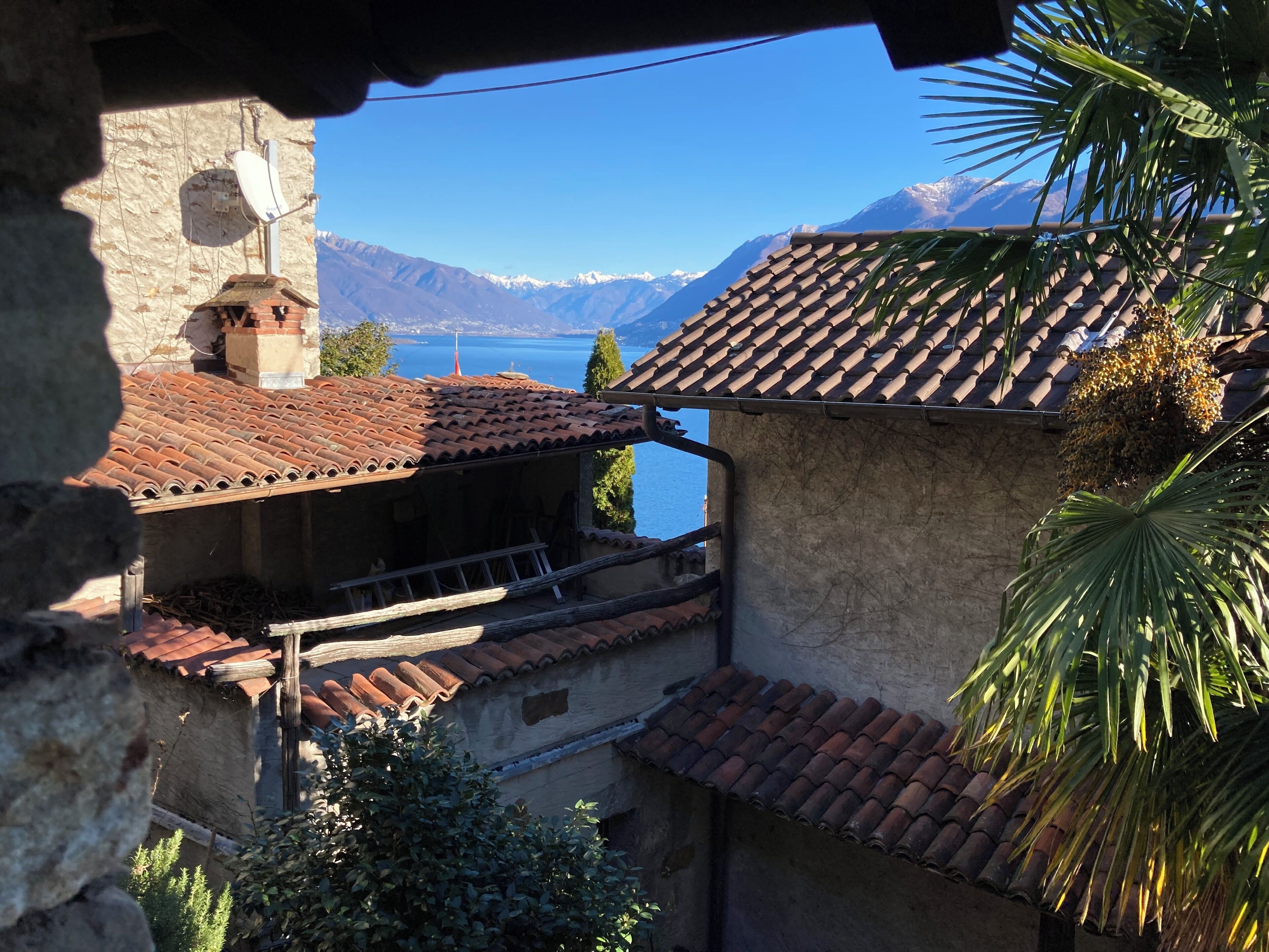 A traditional building with a tiled roof, a balcony, and a view of a lake and mountains.
