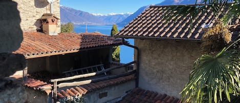 A traditional building with a tiled roof, a balcony, and a view of a lake and mountains.