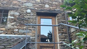A stone building with a wooden door and a metal staircase. - Come stay in our "Little Nest"! (Brissago)