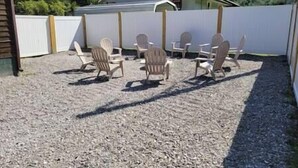 An outdoor seating area with Adirondack chairs and a gravel ground. - The Mate Creek House, The Mate Creek House (Mingo County)