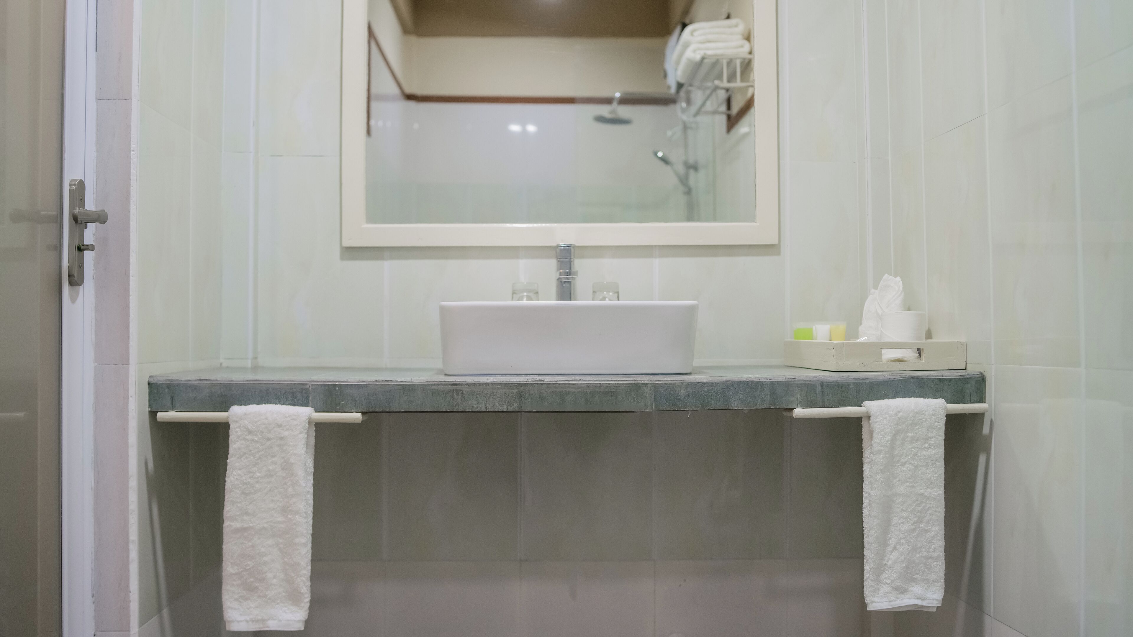 A bathroom with a white sink, two towels hanging on towel bars, and a mirror above the sink.