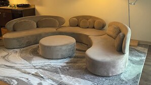 A modern living room with a sectional sofa, ottoman, and a floor lamp. - Modern Downtown Apartment Near UAB (Birmingham)