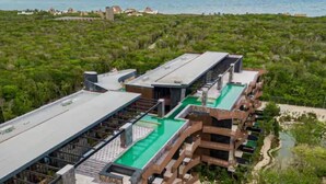 Un hotel moderno con piscina en la azotea y vistas a la vegetación circundante y la costa.
