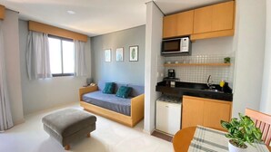 A compact living space with a sofa bed, kitchenette, and a dining area. - Flat confortável próximo ao metrô (São Paulo)