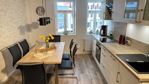 Una cucina moderna con mobili in legno, un tavolo da pranzo con sedie, una sveglia e una finestra con vista sugli edifici.
