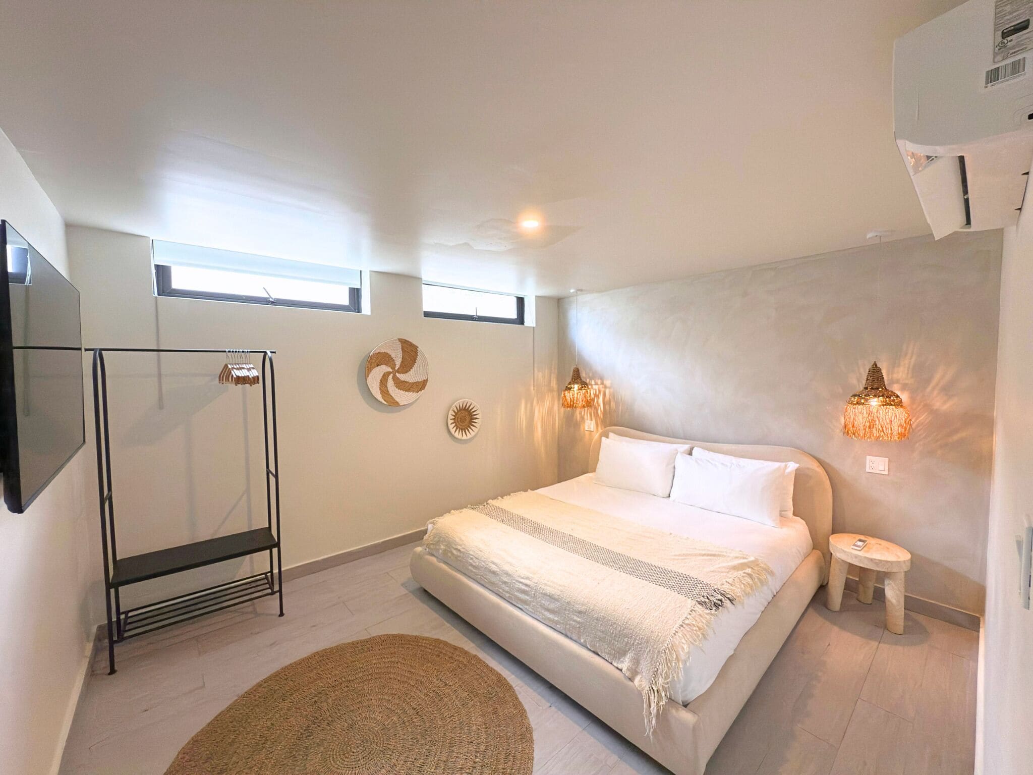 Une chambre moderne avec un grand lit, un grand miroir et deux lampes fixées au mur.