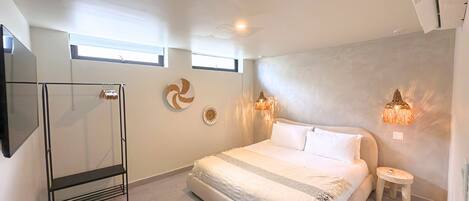 Une chambre moderne avec un grand lit, un grand miroir et deux lampes fixées au mur.