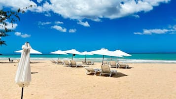 Una playa cerca, arena blanca, sillas reclinables de playa, sombrillas