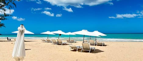 In Strandnähe, weißer Sandstrand, Liegestühle, Sonnenschirme