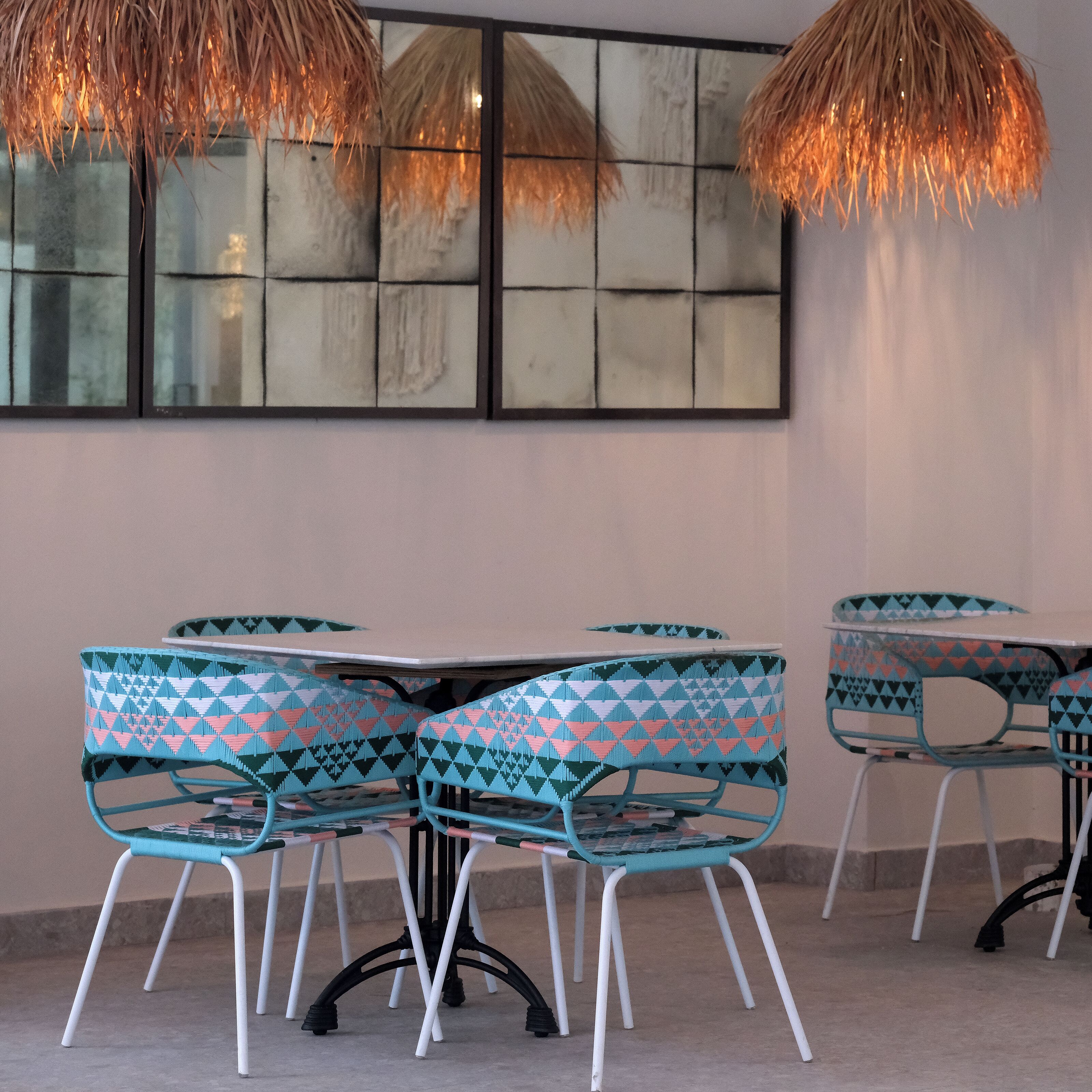 A dining area with a table and chairs, a wall with a large mirror, and hanging lights.