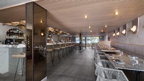 A restaurant with a bar area, high stools, and long tables. - Bali Hotel Adults Only Isla Verde, a Trademark by Wyndham (Carolina)