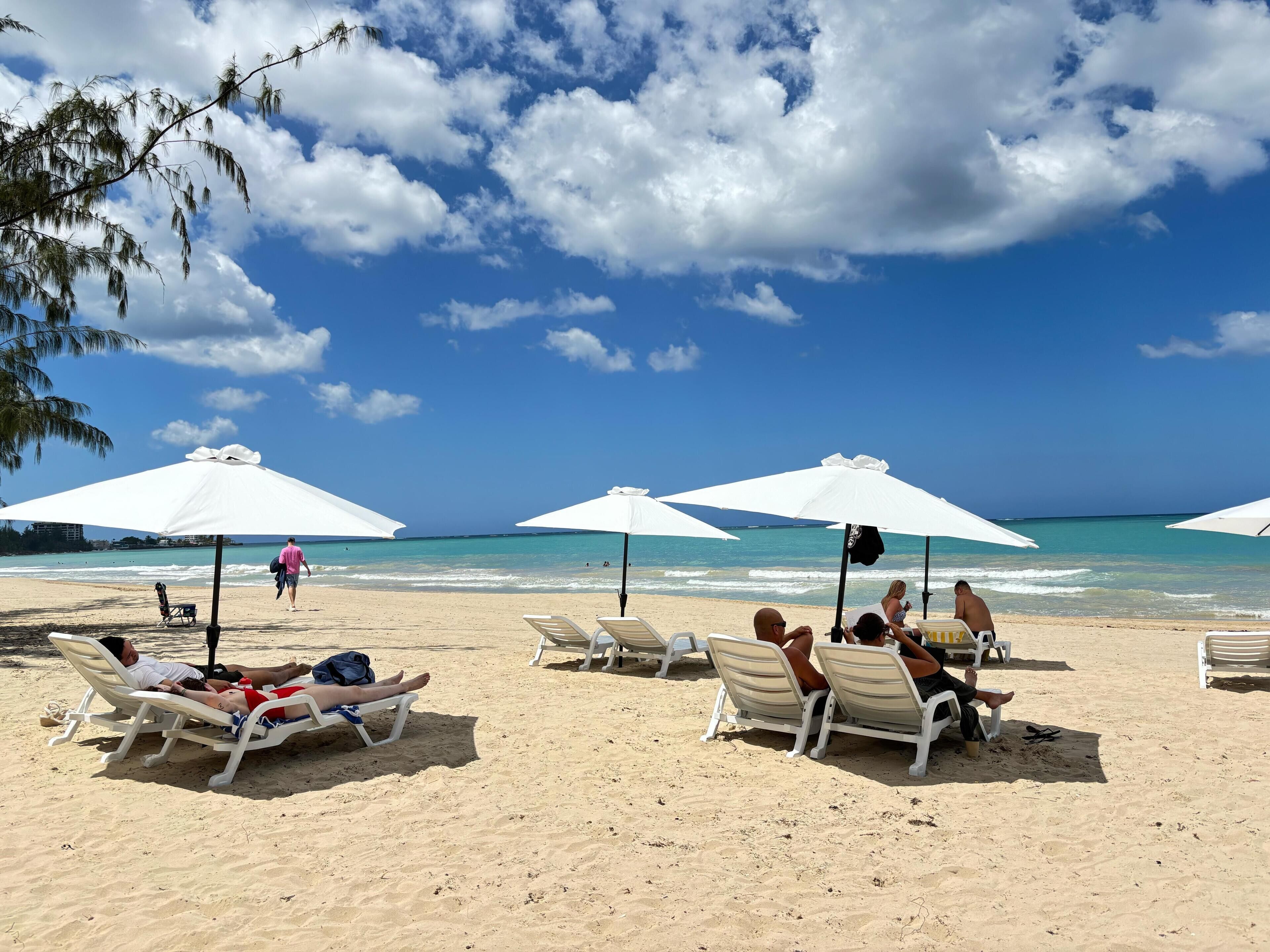 A beach with white umbrellas and lounge chairs.