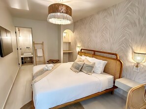 A modern bedroom with a large bed, a wooden headboard, and a chandelier. - Bali Hotel Adults Only Isla Verde, a Trademark by Wyndham (Carolina)