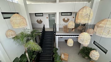A modern interior with a staircase, wicker hanging lights, and potted plants.