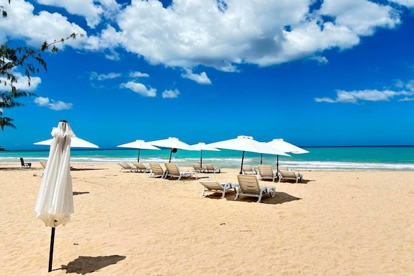 Una playa cerca, arena blanca, sillas reclinables de playa, sombrillas