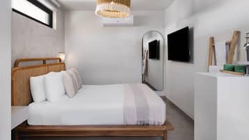 A bedroom with a bed, a television, a mirror, and a window.