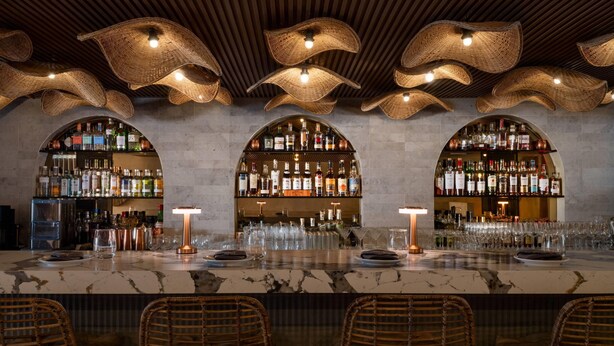 A bar area with a marble countertop, wicker chairs, and a ceiling with woven light fixtures. - Bali Hotel Adults Only Isla Verde, a Trademark by Wyndham (Carolina)