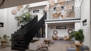 A modern interior with a black staircase, wicker furniture, and hanging light fixtures. - Bali Hotel Adults Only Isla Verde, a Trademark by Wyndham (Carolina)