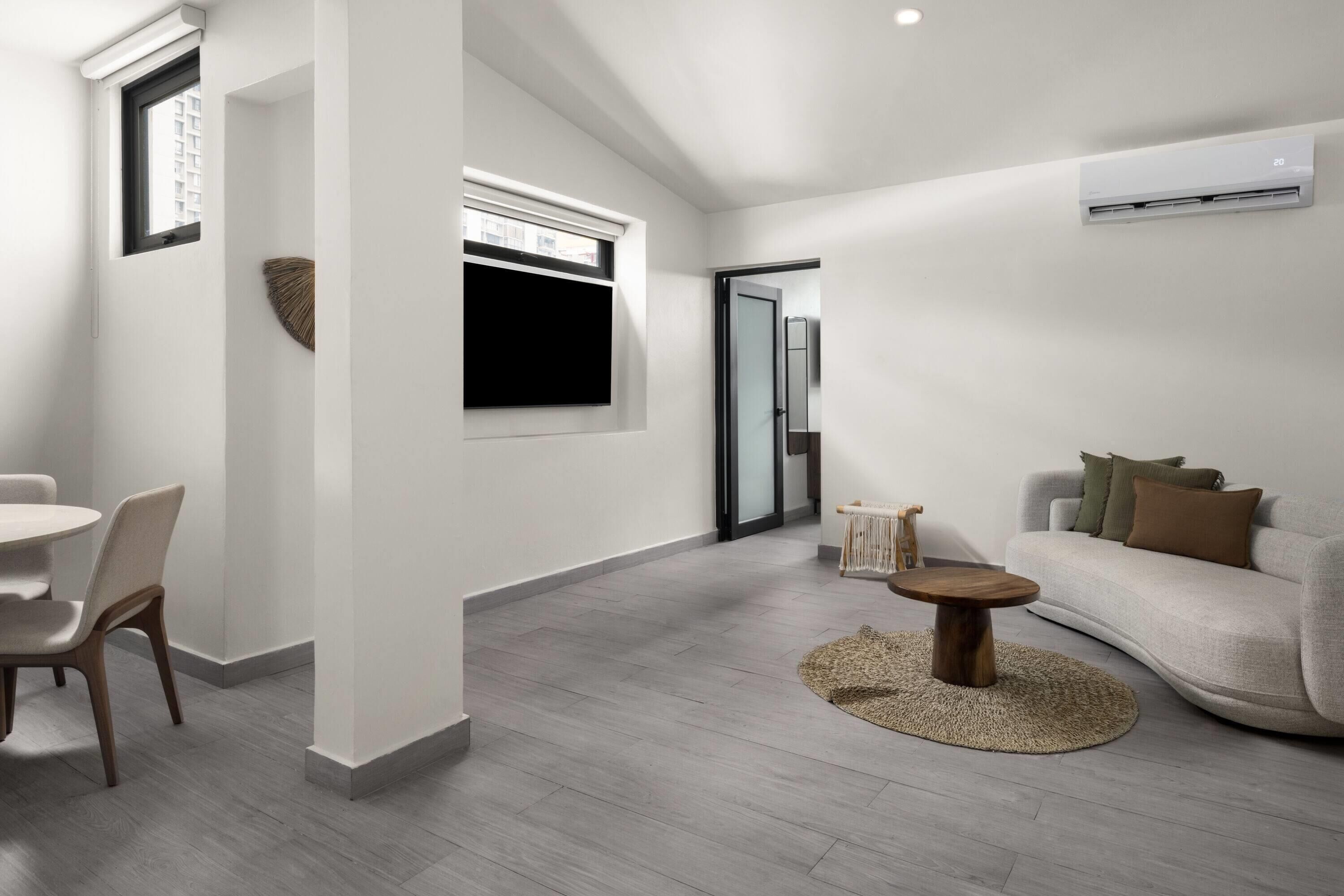 A modern living room with a sofa, a round coffee table, and a dining area with chairs.