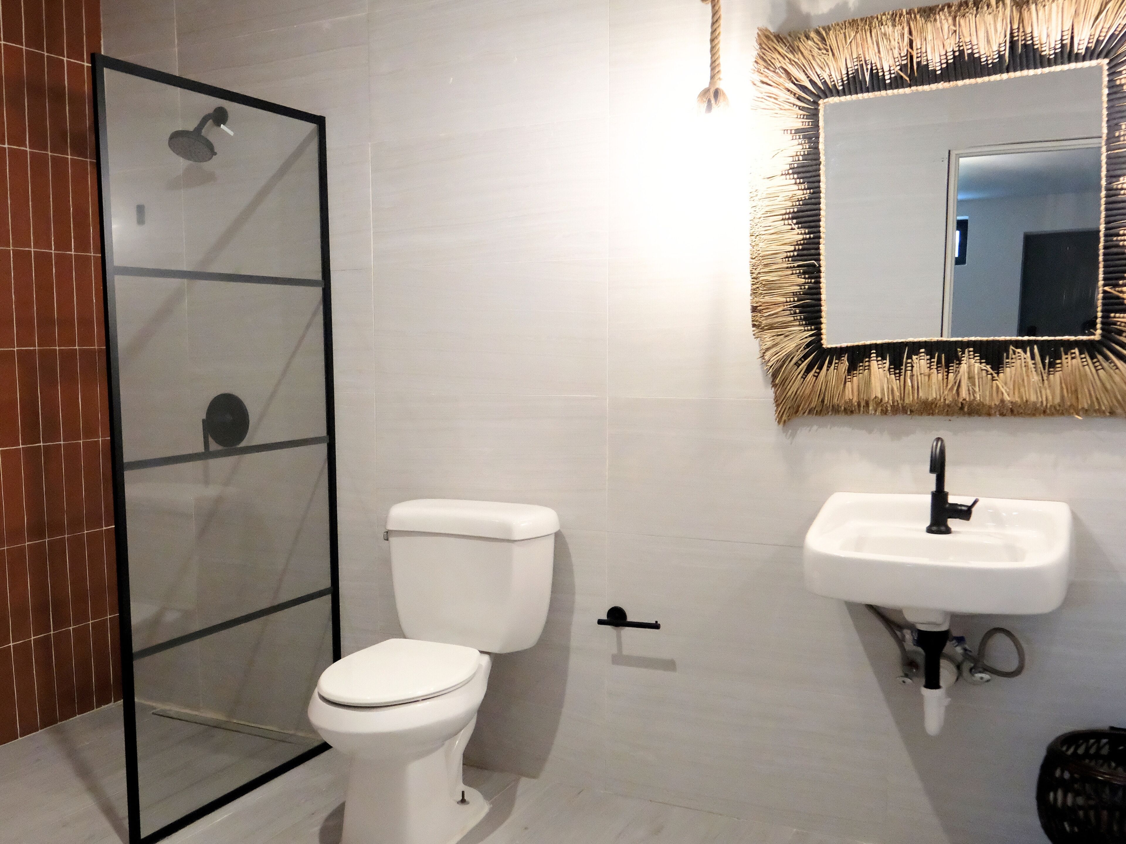 Un baño moderno con cabina de ducha de vidrio, inodoro blanco y lavamanos con espejo.
