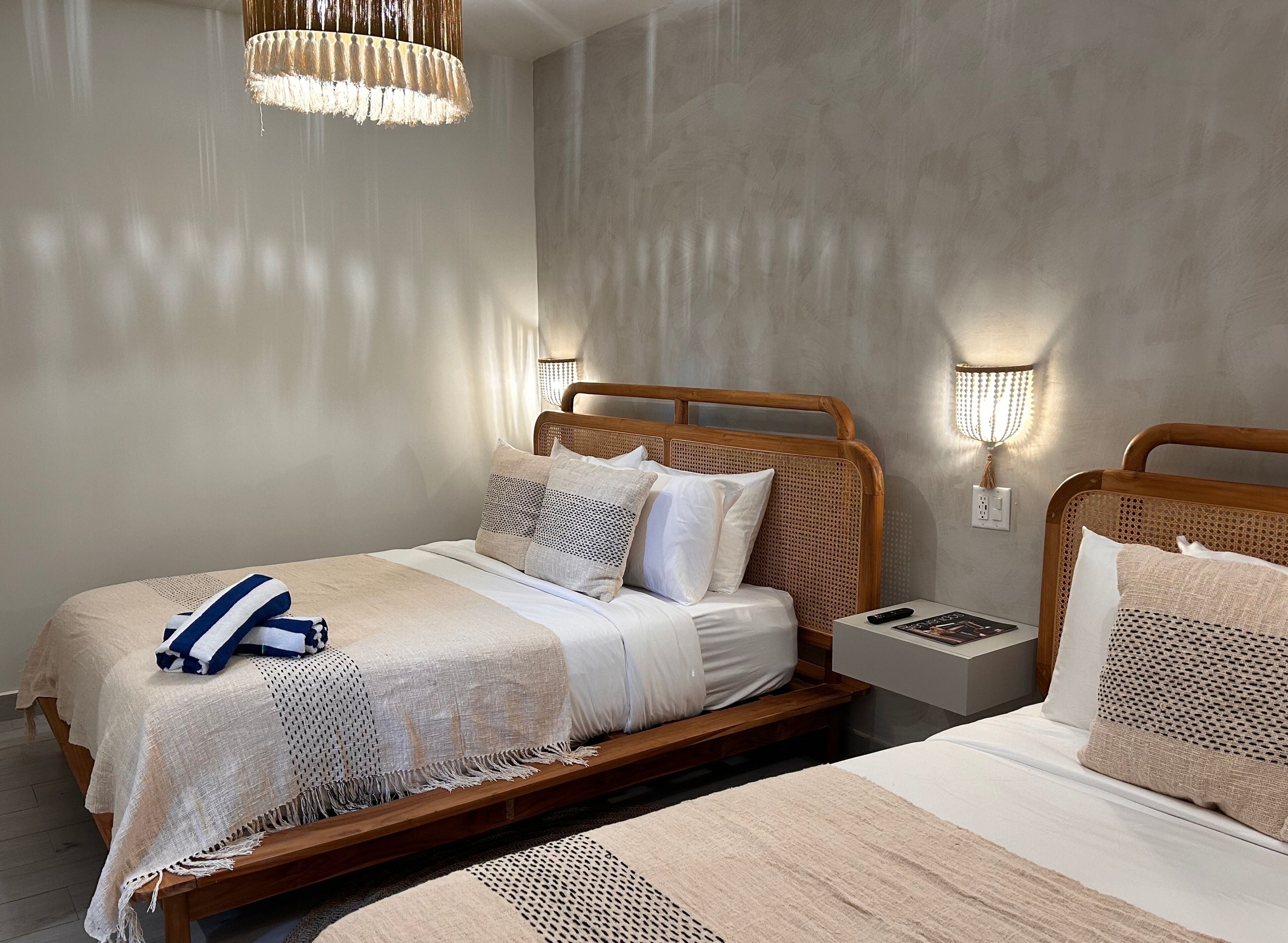 Ein modernes Schlafzimmer mit einem Holzbettgestell, einem Nachttisch mit Lampe und einer Pendelleuchte.