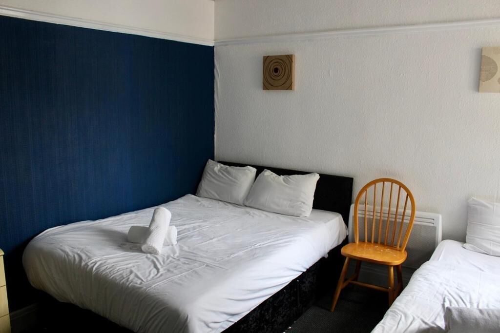 A hotel room with a bed, a chair, and a wall-mounted artwork.