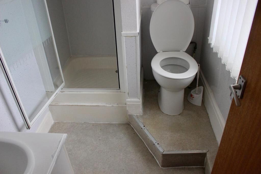 A small, compact bathroom with a toilet, a shower area, and a bathtub.
