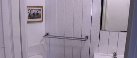 A bathroom with a toilet, a sink, a towel rack, and a framed photograph on the wall.