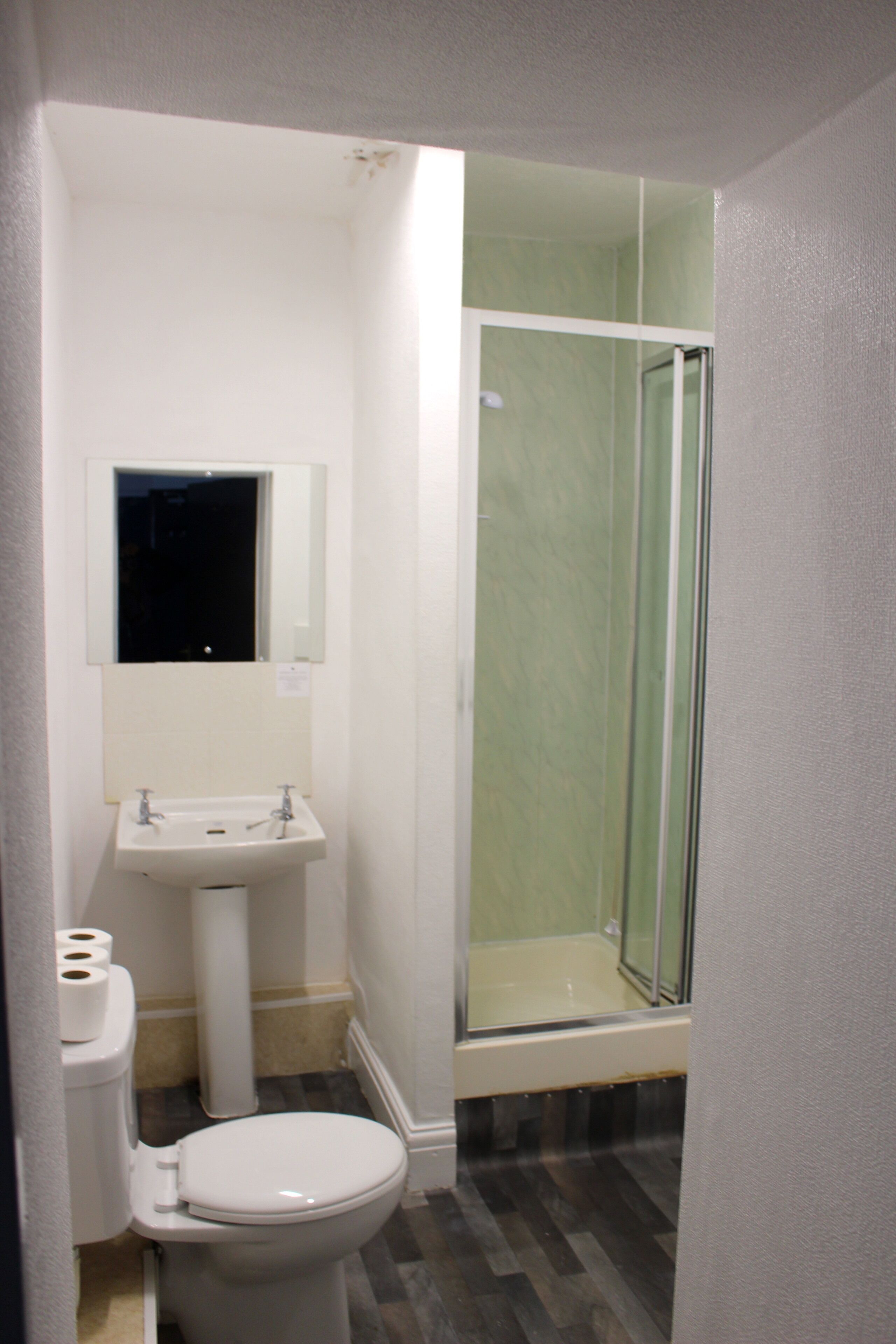A bathroom with a toilet, sink, and glass shower enclosure.