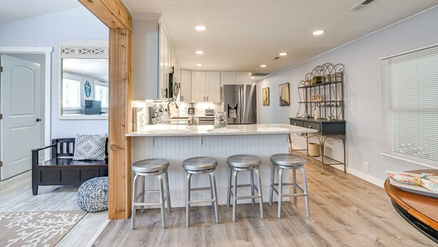 A modern kitchen with a central island, bar stools, and a wooden ceiling beam. - private beach,gated parking,showers bathrooms (Myrtle Beach)