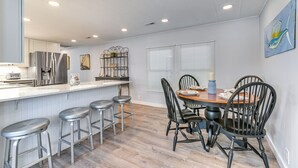 A modern kitchen with a central island, bar stools, and a dining table with chairs. - private beach,gated parking,showers bathrooms (Myrtle Beach)