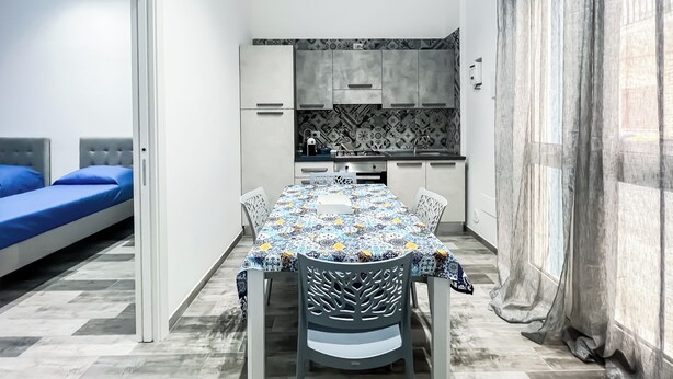 Un espace de vie compact comprenant une table à manger, des chaises, un coin cuisine et un lit.