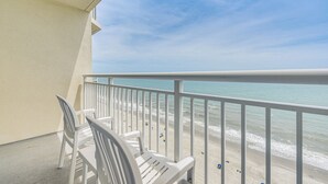 Un balcone con sedie bianche e vista sulla spiaggia.