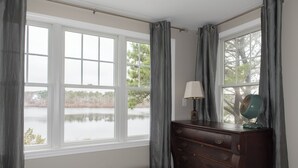 Ein Schlafzimmer mit großem Fenster, einem Schminktisch und einer Lampe.