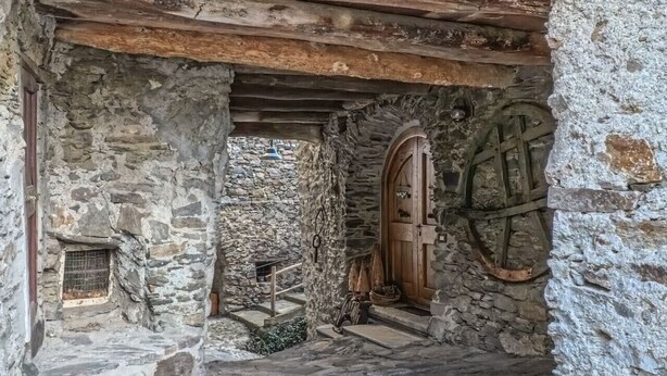 A stone building with a wooden door and steps leading to a higher level. - Appartamento Panoramico Edolo (Vico)