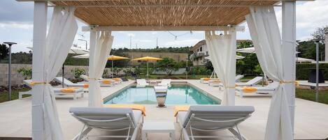 A poolside area with white lounge chairs, yellow towels, and umbrellas.